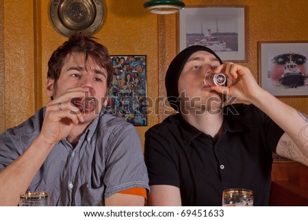 Two friends sitting in a pub and drinking hard liquor