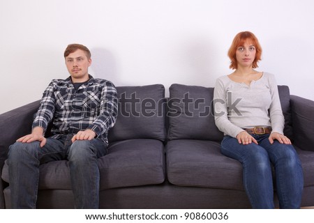 A young couple in a bad mood is sitting on the sofa