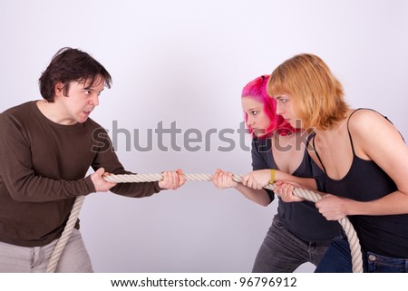 Two women and a man are pulling a rope