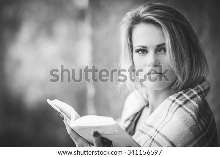 young, beautiful girl, wrapped in a blanket warm blanket, reading a book