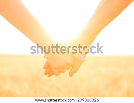 Closeup of two 2 people, persons mother and daughter holding, keeping hands isolated in the sunny field, on agricultural land, wheat field. Summer, travel, sun, sunshine. Bright future, team concept.