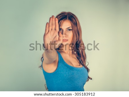 Closeup portrait young angry serious woman showing her denial No Stop talk to hand gesture with palm outward isolated green wall background Negative human emotion face expression feeling body language