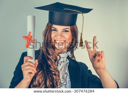 Portrait closeup beautiful smiling latina graduate graduated student girl young woman in cap gown showing peace  holding diploma scroll isolated green background wall. Celebrating graduation ceremony