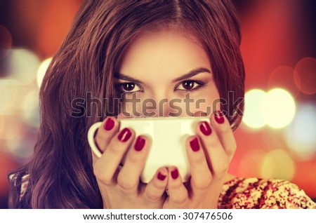 Coffee. Young beautiful Girl woman drinking Tea Cappuccino in trendy cafe shop. Beauty Model with Cup of Hot Beverage. Closeup portrait, warm colors. Human emotions positive facial expressions feeling