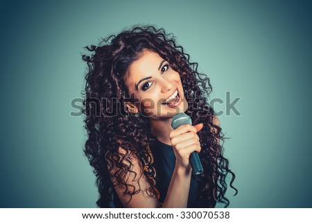 Singer. Closeup portrait head shot sexy beautiful happy young woman lady girl singing with microphone smiling isolated green background wall. Positive human emotion expression feeling life perception