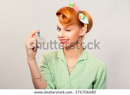 Girl with perfume. Closeup red head beautiful young woman pretty smiling pinup girl green button shirt holding bottle of perfume and smelling aroma looking at you camera, retro vintage 50\'s hairstyle