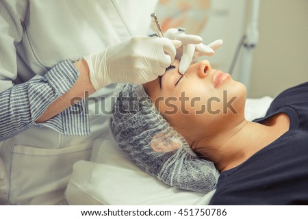 Microblading eyebrows work flow in a beauty salon. Woman having her eye brows tinted. Semi-permanent makeup for eyebrows.