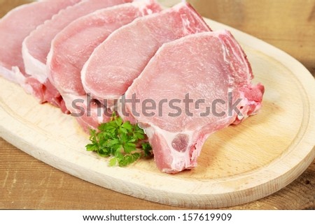 Raw pork loin chops on the wooden plate