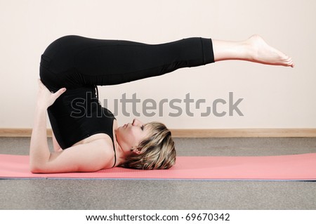 young woman doing yoga exercises on the pink wall background