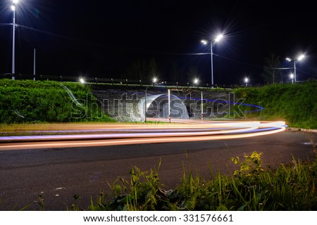 Night road with tracer by car, lit lamps.