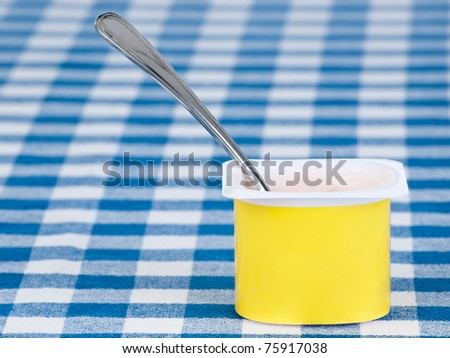 yogurt pot with spoon on blue and white background