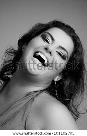 Female Plus size model posing in the studio, bw face portrait, on grey background. The woman is smiling in a happy manner. Good for concept of health, happiness, dieting, obesity, weight loss.
