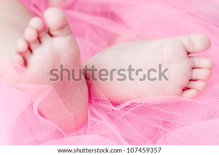 Close up of baby\'s feet on a pink background for a candid and emotional sense.