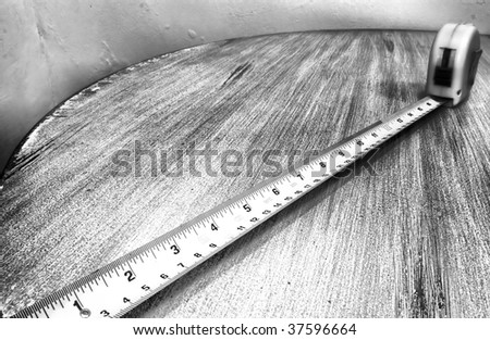 A ruler tape on top of an old table, photo in black and white.