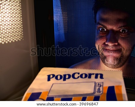 A man excited to get his popcorn done at the microwave, perspective from inside de microwave.