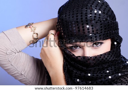 Beautiful woman  covering her face with a black hijab with beautiful bright spots on it.