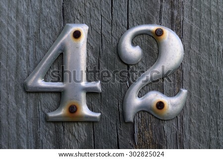 Metal Number 42 Nailed to Weathered Wood Post