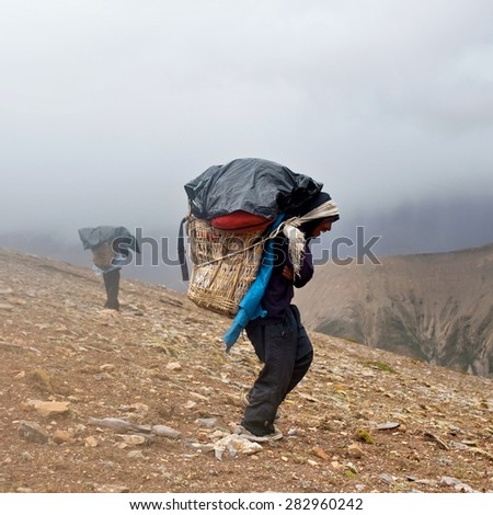 DOLPO, NEPAL - SEPTEMBER 12: Porters carrying heavy load walking across Himalayan pass on September 12, 2011 in Upper Dolpo restricted area, Nepal