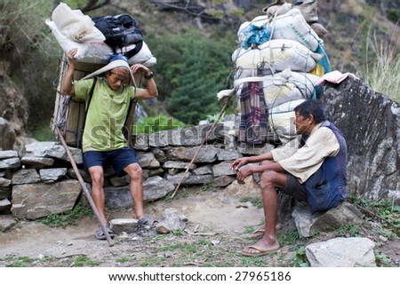 ANNAPURNA CIRCUIT, NEPAL - APRIL 20: Two porters carry heavy load in the Himalaya, Nepal April 20, 2008 in Annapurna, Nepal. Annapurna trail is well known for its trekking activities.