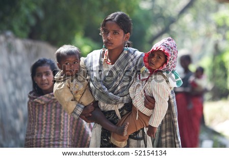 KATHMANDU, NEPAL - NOVEMBER 08: A young nepalese woman with two children begs for money on the road on November 8, 2009 in Kathmandu, Nepal.