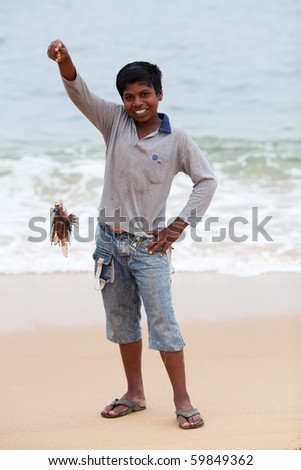 VARKALA, SOUTH INDIA - FEBRUARY 11: Indian boy Pradip, 10, with poison lionfish on the shores of the Arabian Sea on February 11, 2010 in Varkala, State of Kerala, South India