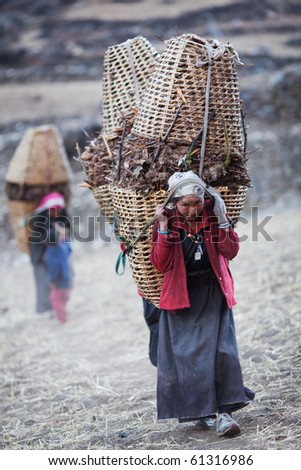 MANASLU AREA, NEPAL - NOVEMBER 28: Several Tibetan women in national clothes with basket on the road on November 28, 2009 in Gorkha District, Nepal.