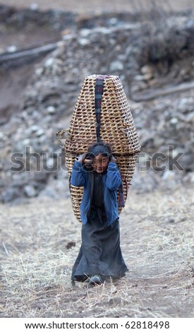 MANASLU AREA, NEPAL - NOVEMBER 28: Portrait of an unidentified Tibetan girl with basket from village of Tibetan refuges s on November 28, 2009 in Gorkha District, Nepal.