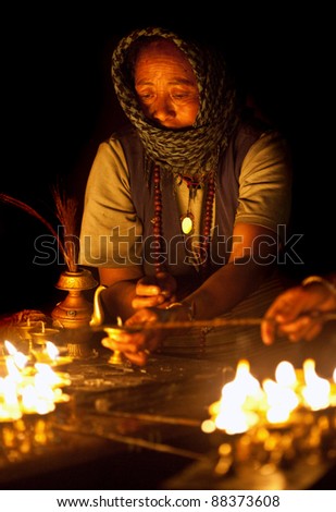 KATHMANDU, NEPAL - FEBRUARY 28: An unidentified Tibetan woman lights incense butter candles in honour of Losar holiday on February 28, 2010 in Boudhanath, Kathmandu Valley, Nepal