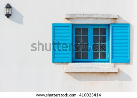 Colorful blue window and Detail of house exterior on white wall.