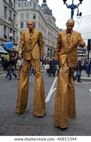 LONDON - DECEMBER 5: Two golden men on stilts at Shop West End VIP (Very Important Pedestrians) Day in London West End, December 05, 2009 in London, England.
