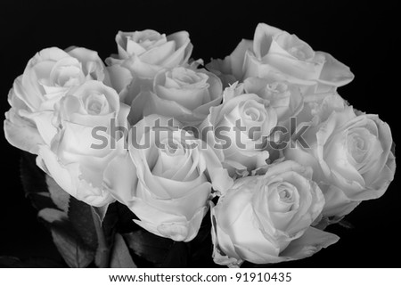 Black and white image of a bouquet of white roses over black background