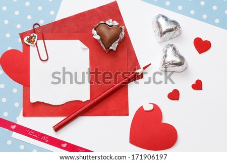 Valentine's day love message, unfinished, on white paper with pencil, red hearts in silver foil isolated on blue with white dots background (polka dot)
