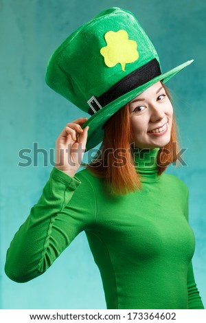 Red hair girl in Saint Patrick's Day party hat having fun isolated on green grunge background