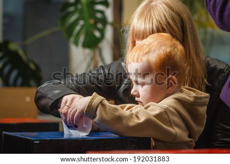 DONETSK, UKRAINE - MAY 11: Kid with mother voting at one of the polling stations for independence referendum, on may 11, 2014 in Donetsk.