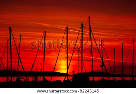 An intense sunset silhouettes sailboats in a harbor - Powell River, British Columbia.