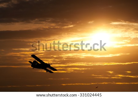 Silhouette of the propeller plane flying high in the sky on sunny summer day.