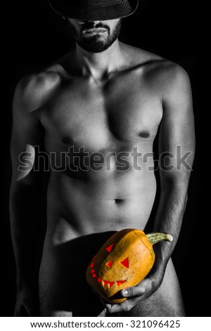 Naked man with hat holding creepy carved halloween pumpkin