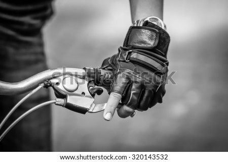 Close up bicycle rider\'s hands on a bicycle handlebar. black and white filter