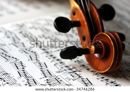 The scroll of an old Italian violin on sheet music.