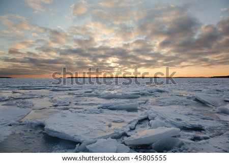 A winter landscape in the sunset with packed ice in the sea.
