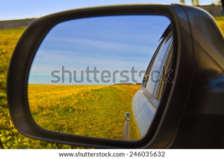 View through a car mirror. Blue and Yellow reflection in mirror. Ukrainian rural landscape