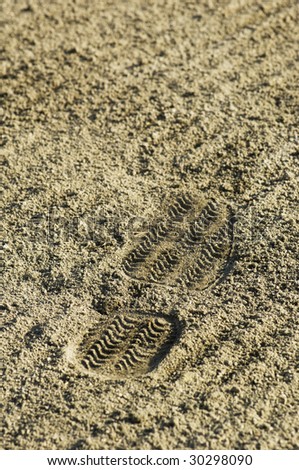 A single shoe print in textured sand