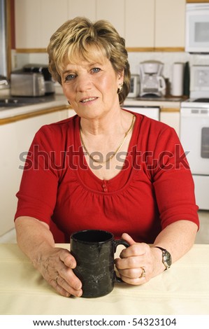 Woman sitting in her kitchen with a mug in her hand, taking a break