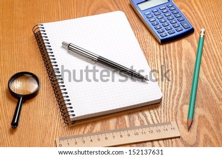 Desk with sheet of paper, calculator and stationery objects seen from above