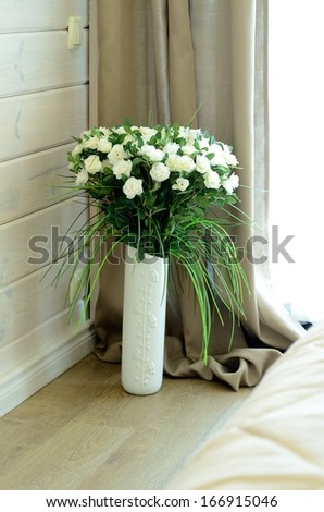 Beautiful white roses in vase on room background