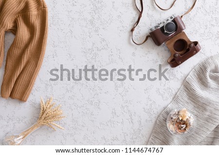 Vintage flat lay, top view. Retro camera, flowers and knitted clothes on office plaster desk table, copy space. Autumn background