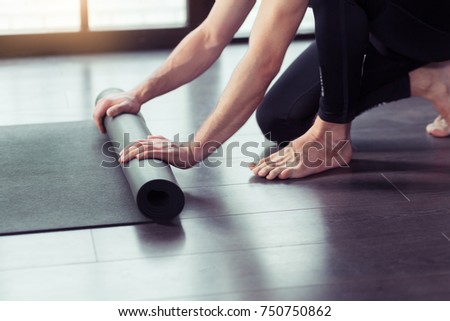 Cropped image of men hands rolling black yoga mat