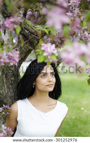Young, South Asian woman standing in a park under an apple blossom tree