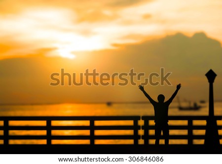 Silhouette successful man or winner man on Beautiful evening  sunset above the sea and over blur boat