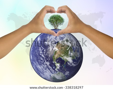 Two human hands show symbol of love for perfect growing tree plant on the world on blurred natural background of sky and cloud with world map. pastel color concept blue, pink . world photo from NASA
